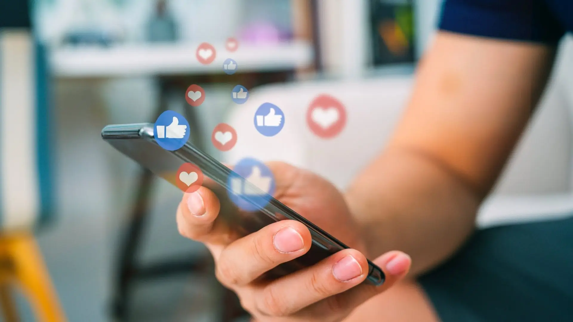 Hand holding a smartphone with floating engagement icons, illustrating how to maximize social media presence.